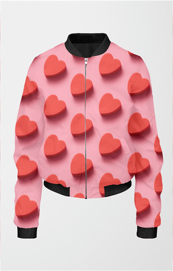 A pink bomber jacket for women with a design of red, three-dimensional hearts scattered across. The jacket has a black collar, cuffs, and hem.