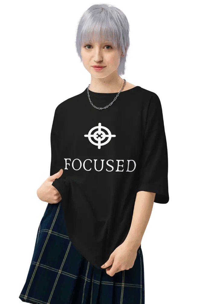 Person in black t-shirt with ‘FOCUSED’ print and plaid skirt pointing at shirt design.