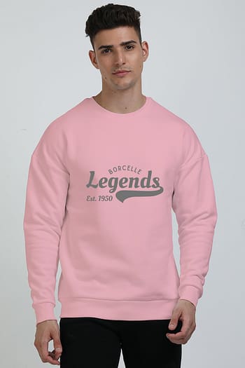 A person wearing a cozy oversized Light Baby Pink sweatshirt with Borcelle Legends Est. 1950 text, standing against a plain background.